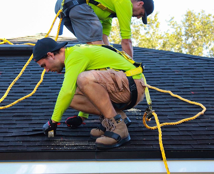 A GreenBros roofer working off a rope line