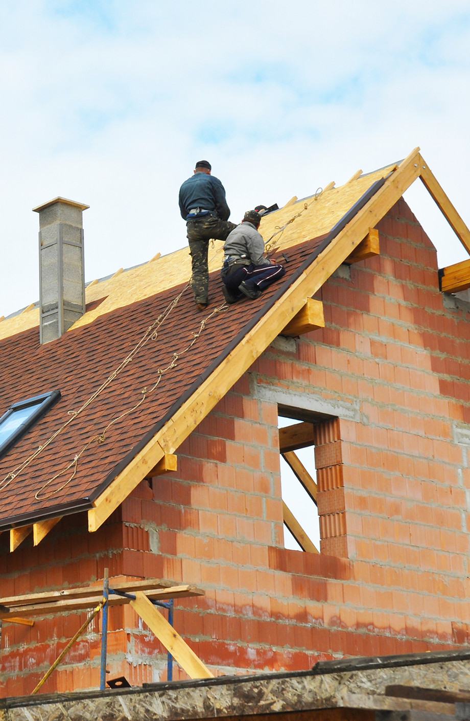A crew roofing a house still under construction