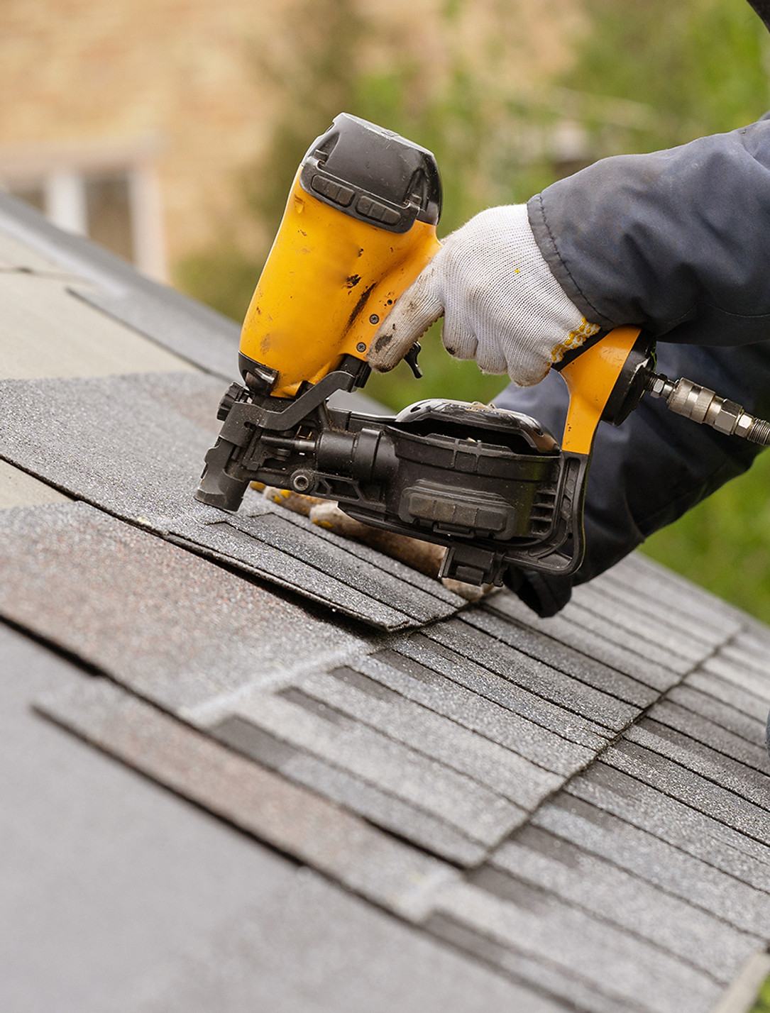 Shingles being nailed down over new underlayment