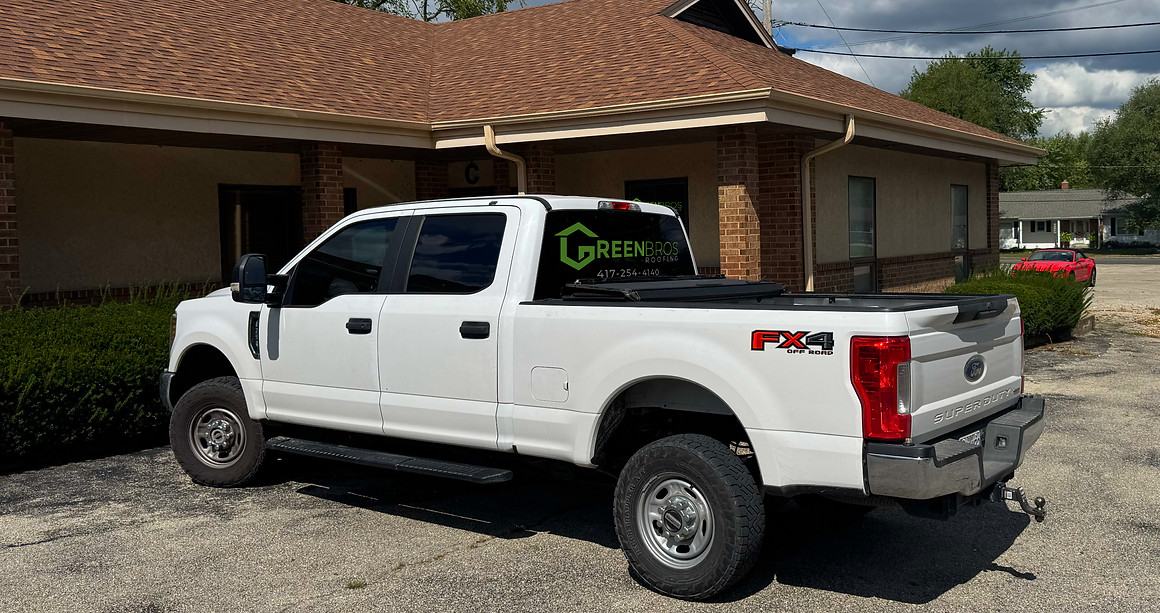 A GreenBros Roofing truck outside a customer's home